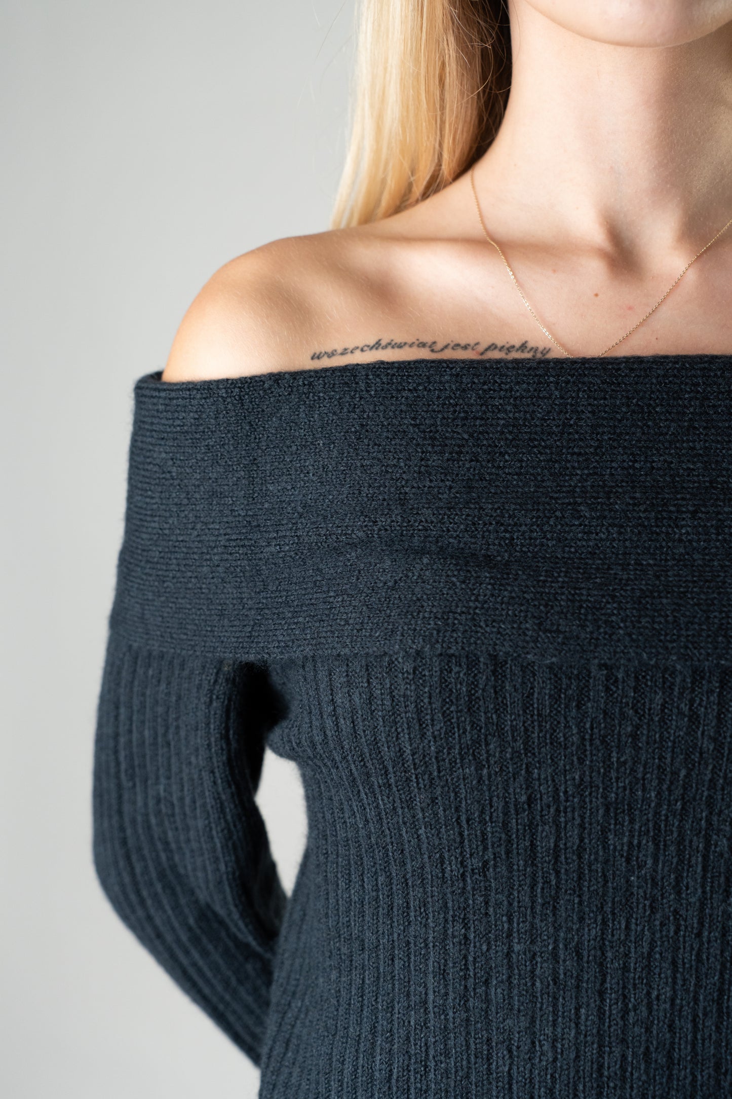 Close-up of the black Amara Off-Shoulder Sweater showing ribbed knit texture and neckline.