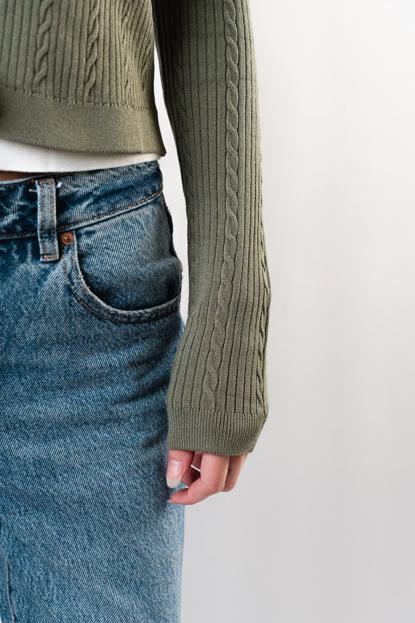 Close-up of the olive Celine Cable Knit Cardigan sleeve showing textured knit pattern.