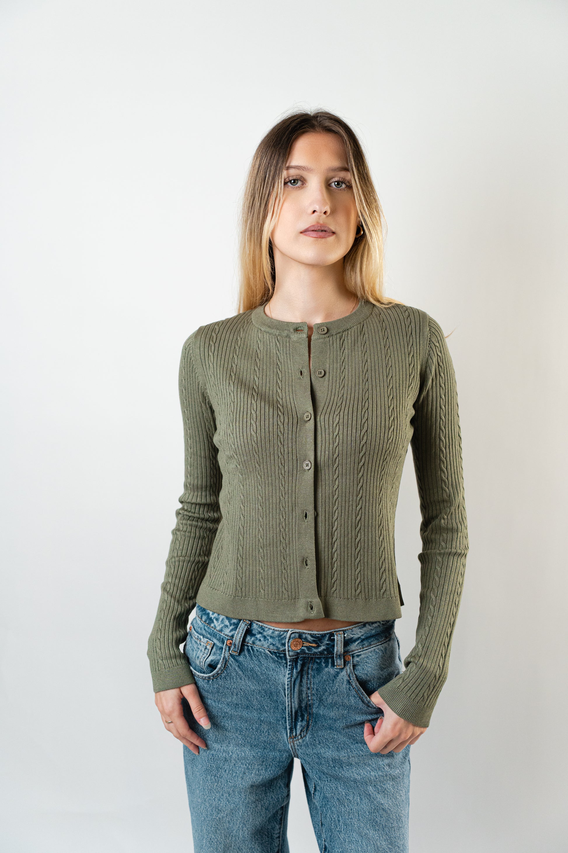 Model wearing the olive Celine Cable Knit Cardigan, a textured button-up knit sweater.