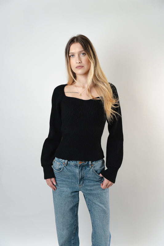 Model wearing the black Olivia Ribbed Sweater with a square neckline and long sleeves.