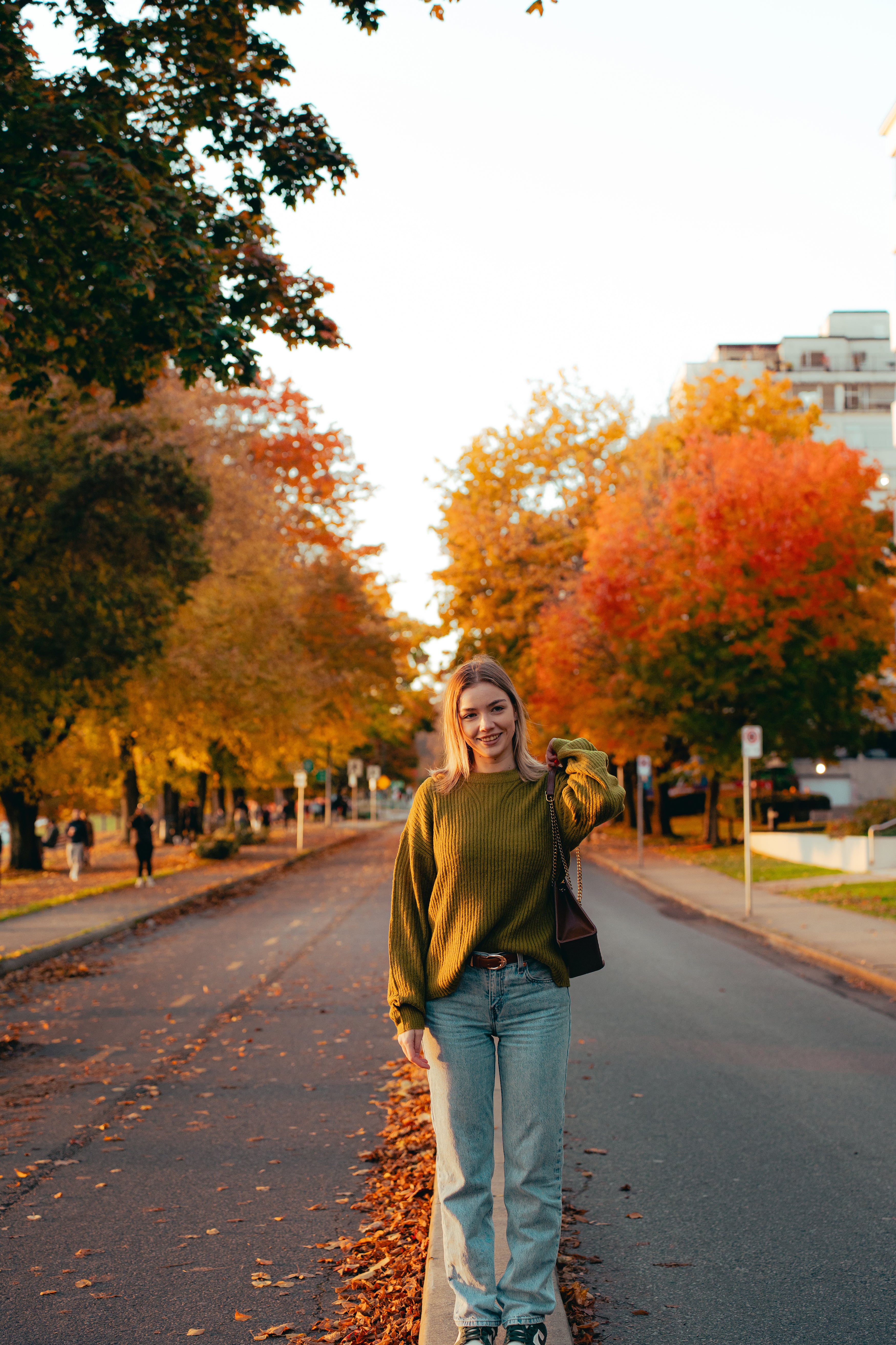 Woman standing on a street with autumn trees in the background